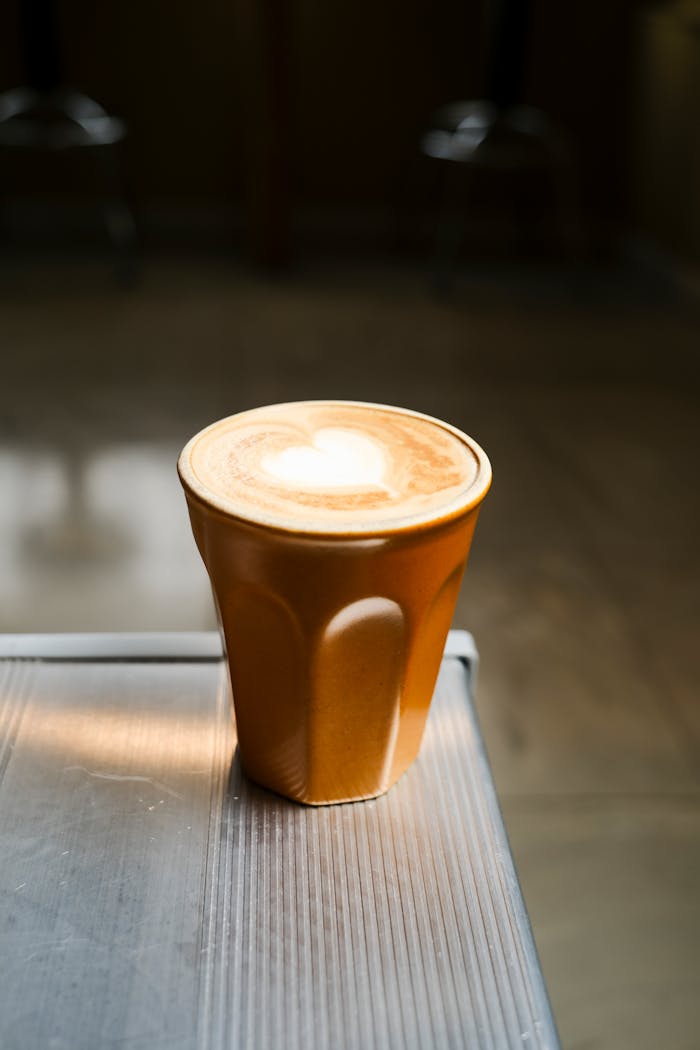 A beautifully crafted heart latte art in a warm cafe setting with soft lighting.
